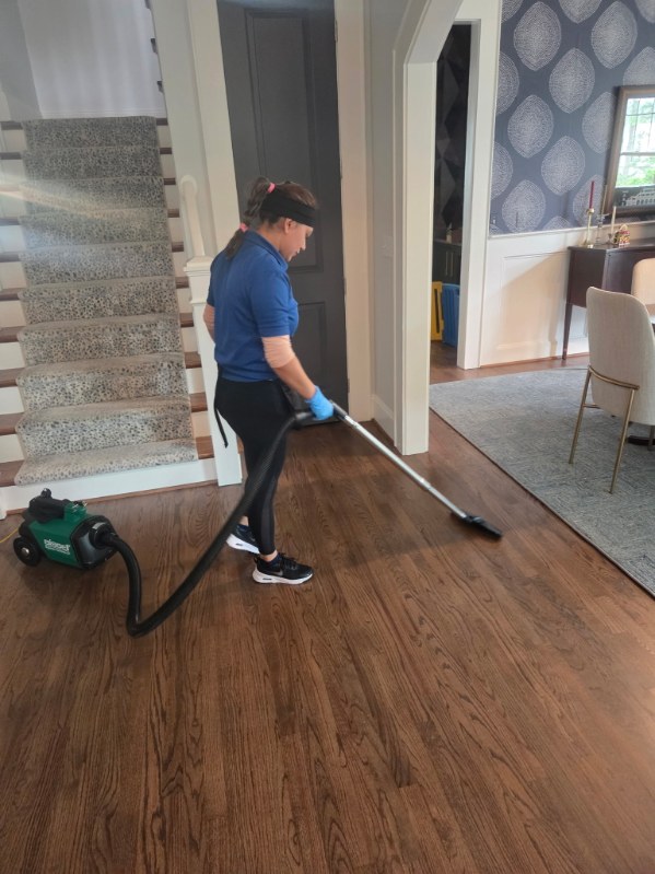 Cleaning people in uniform sweeping hardwood floors
